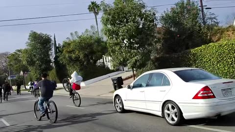 Car Races Through Large Pack Of Bicycles