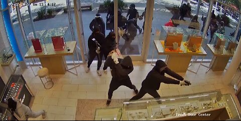 Two dozen people wearing masks and some carrying pickaxes smash jewelry cases and rob store