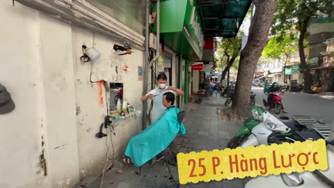 Getting a haircut on the street in Hanoi, Vietnam