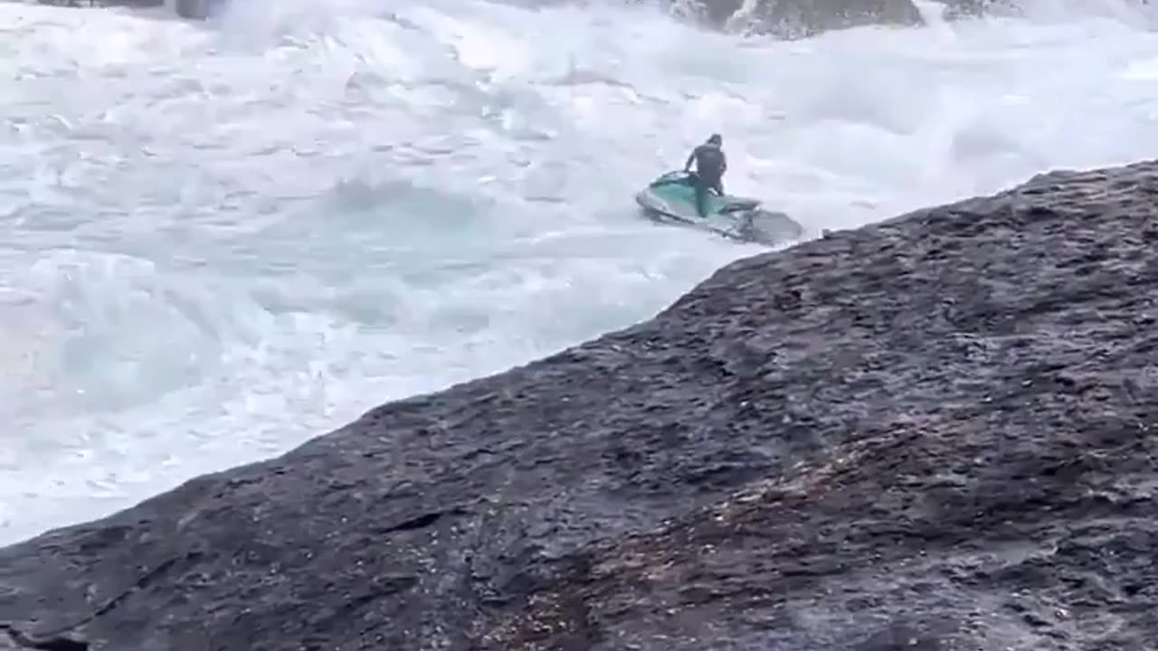 Jet ski person saves a surfer in colossal waves.