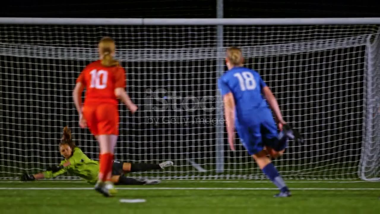 TS Female soccer player scoring a goal at a soccer match at night