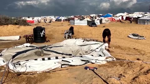 Displaced Palestinians fix their tents after night of heavy wind, rain