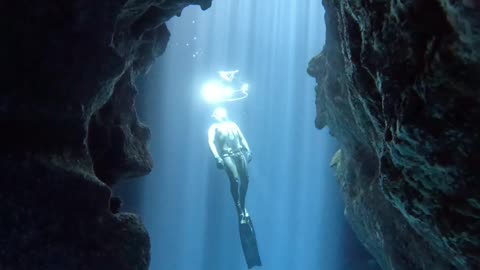 Cave View of a Free Diver Swimming Through Bubble Rings
