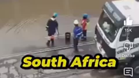 South African workers drain flooded streets with a bucket of water