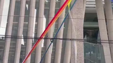 People tearing down a pride flag at a Federal building