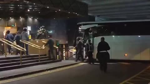 Migrants arrive at night by bus (London)