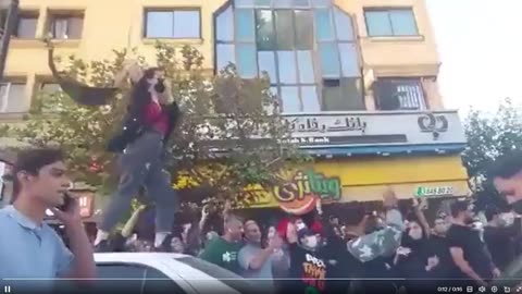 Một người phụ nữ đứng trên một chiếc xe hơi ở Tehran, cởi khăn trùm đầu...