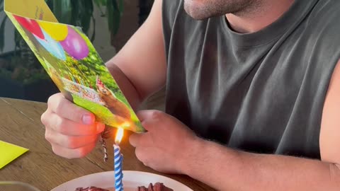 Guy Reading a Birthday Card as the Candle Lights It on Fire