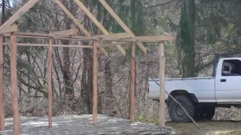A man builds a house with his own hands in the mountains