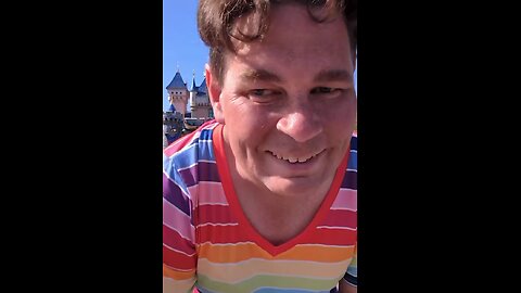 A transgender man twirls in a women's dress at Disney, filming himself with children present.