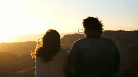 Couples sitting on mountain, strong wind