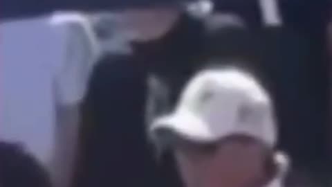 Guys in White and Black standing behind Charlie making what appears to be hand signals.