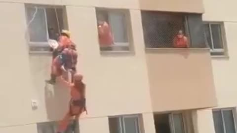 Bomberos salvan a mujer en peligro de caer por la ventana