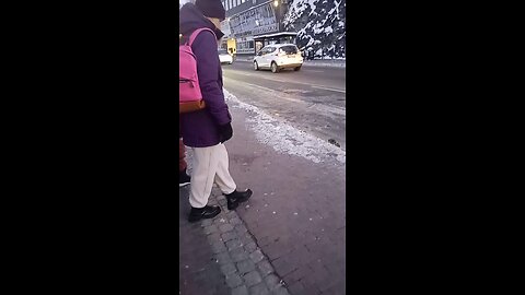 Beautiful young woman is freezing while waiting for the bus. On the street -18°C