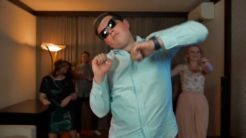 Group of young people dancing happily, while a boy with dark glasses leads them right in front.