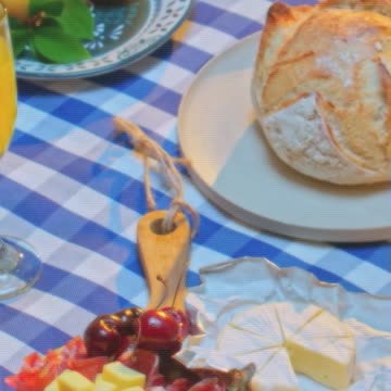 A vertical shot of a beautifully arranged picnic featuring fresh fruits, charcuterie.