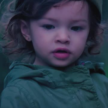 Little girl in nature with a marshmallow on a twig at a campfire