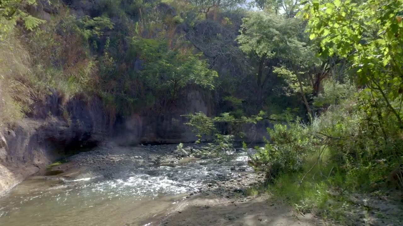 Flying over a relaxing creek full of rock on the countryside