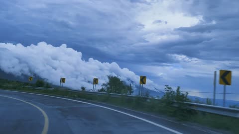 Going down a curved highway through a mountain range