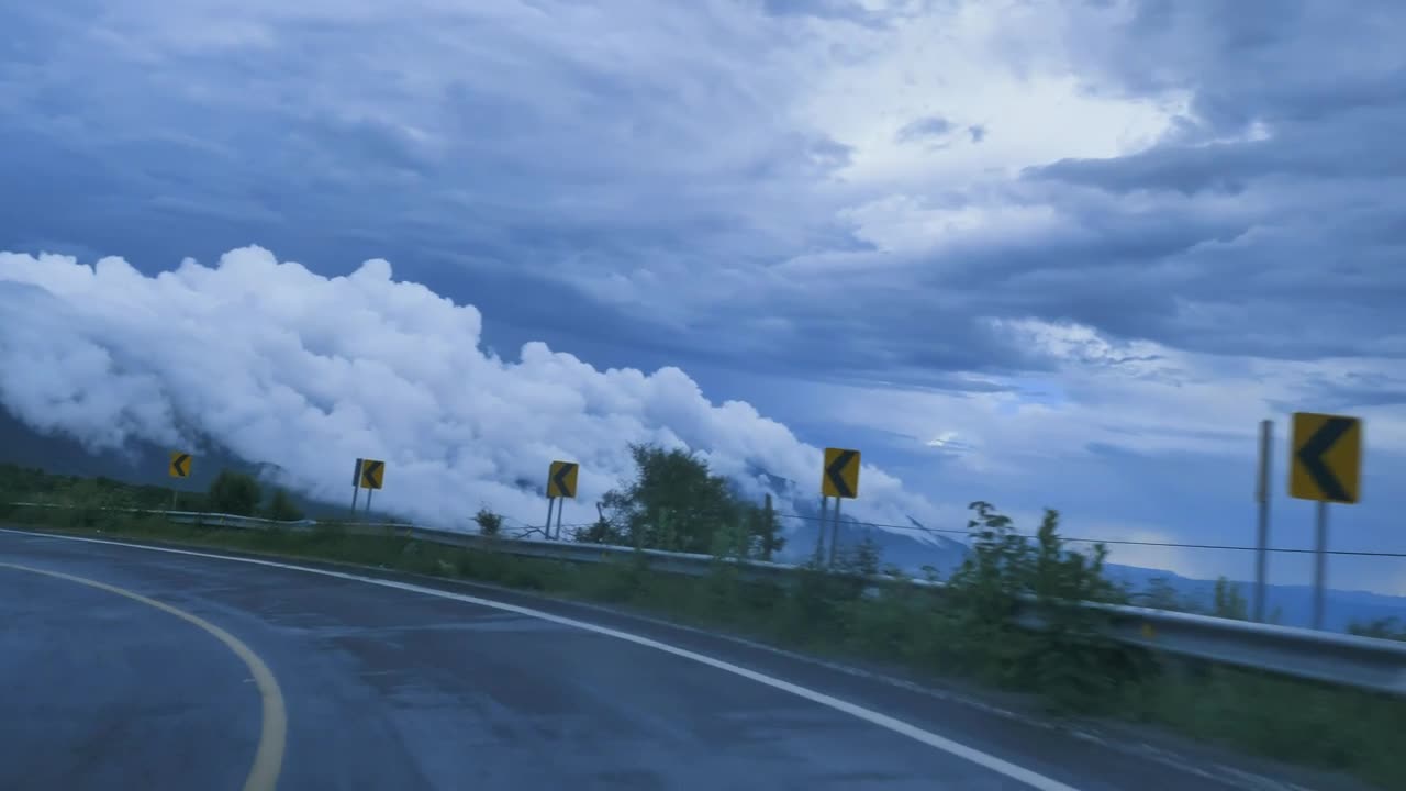 Going down a curved highway through a mountain range