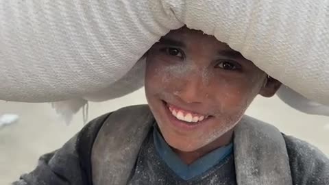 Gazan child walks long distances carrying flour after risking his lif.