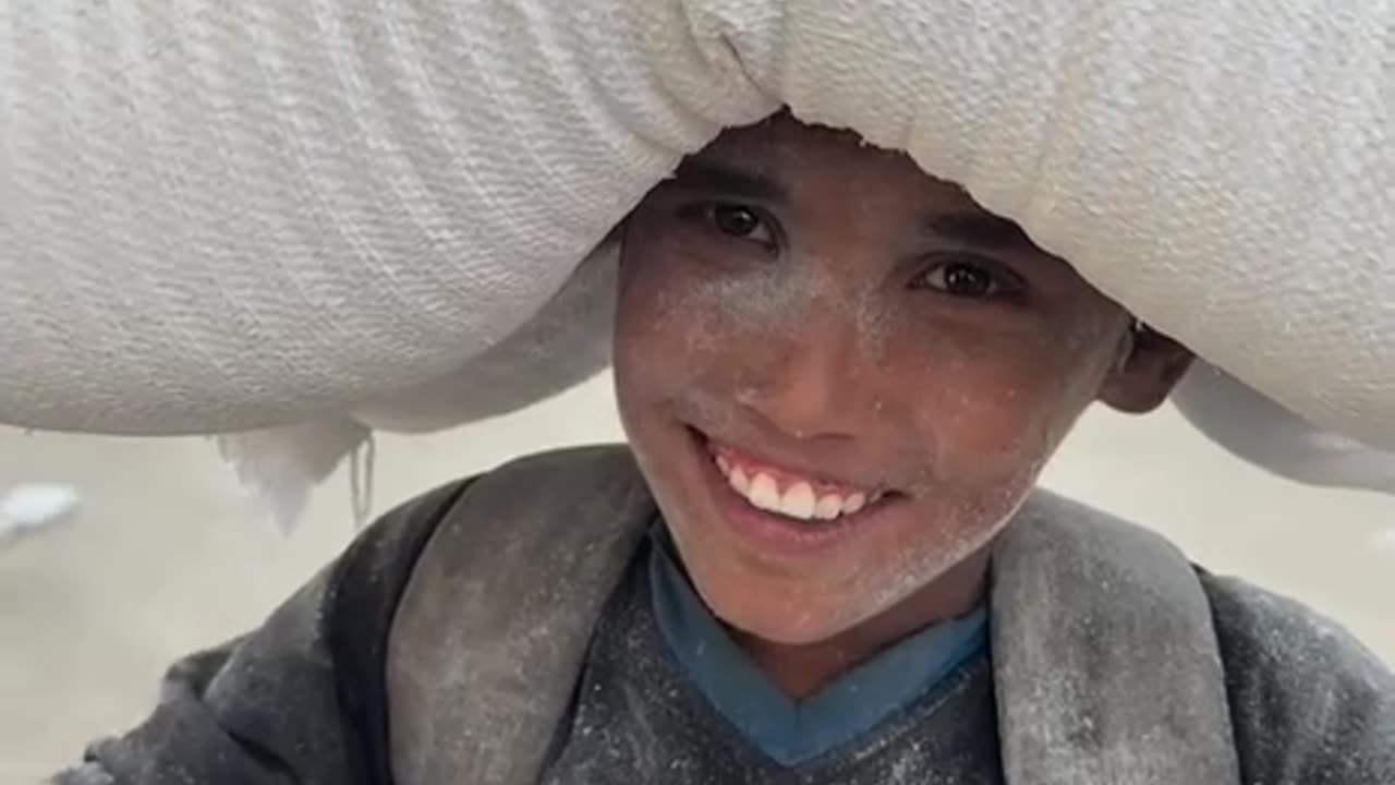 Gazan child walks long distances carrying flour after risking his lif.