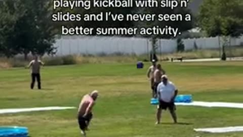 Adults playing kickball with slip and slides