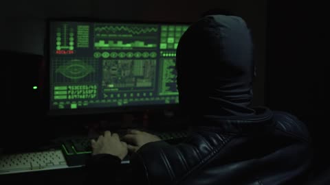 Hacker with balaclava working in front of a computer