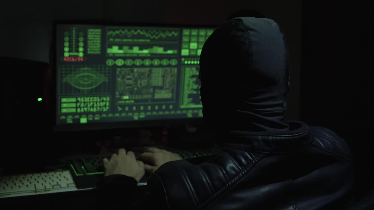 Hacker with balaclava working in front of a computer