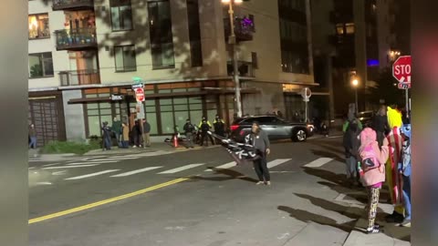 Portland, OR. ICE Building. Theee people in bloc shining lights into the Officer’s