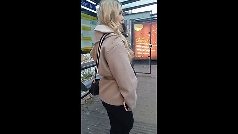 Young beautiful girl is freezing while waiting for the bus. Shaking with small shivering from cold.
