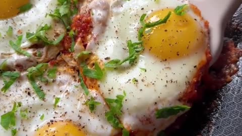 Making a breakfast meal, eggs cooked with tomato paste