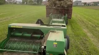A farmer bales hay with his John Deere 348 Baler