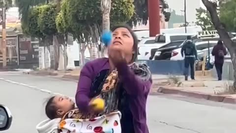 Truly surprised Mother holding her child and showing him the game with both hands in a public place