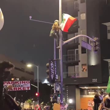 LIVE: ICE protester in Los Angeles climbing a traffic light to raise the Mexico Flag