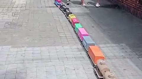 Little Boy Walks Giant Train Down Sidewalk