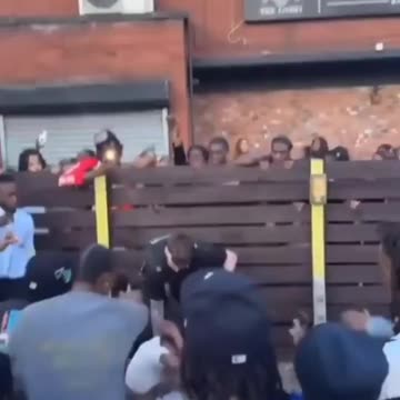 British policeman surrounded by a crowd of black people in Leicester.
