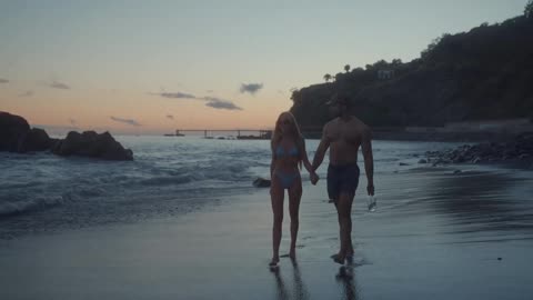 A couple walking by the coastline, almost at night