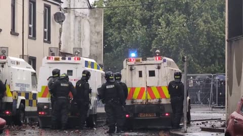 Portadown PSNI officers take shelter behind their vehicles from debris being thrown at them.