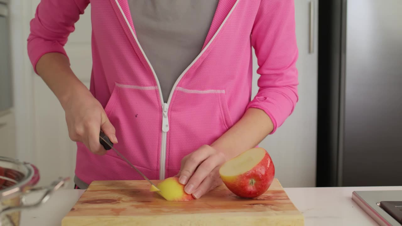 Young woman chopping an apple and some more fruit into slices.