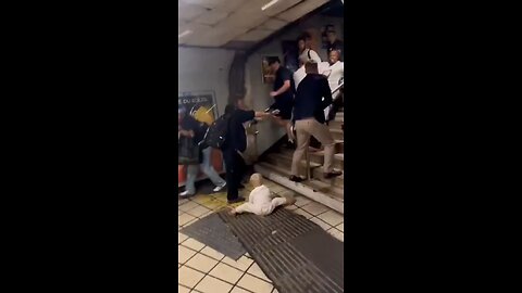 Migrant punches a man holding a baby at a London underground station, baby falling to the floor.