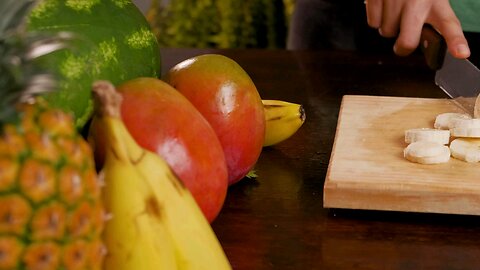 Person cutting banana for a fruit cocktail