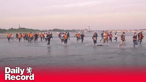 Migrants run across beach into overcrowded dinghy on Gravelines beach, France