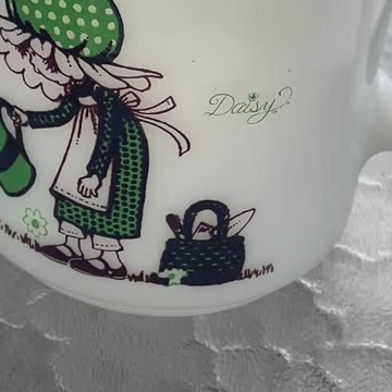 vintage Hazel-Atlas milk glass mug with a green daisy and bunny design from the 1970s.