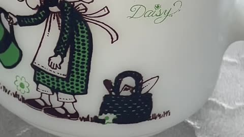 vintage Hazel-Atlas milk glass mug with a green daisy and bunny design from the 1970s.