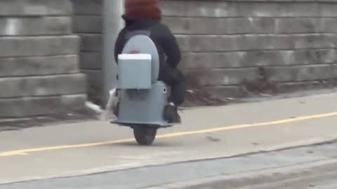 Man Riding a One-Wheeled Toilet Scooter