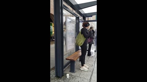 Beautiful young woman in a light tracksuit is freezing while waiting for the bus.