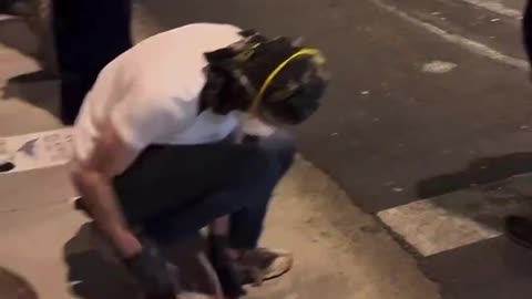 Antifa is using a hammer to break up the sidewalk and create projectiles to attack police officers.