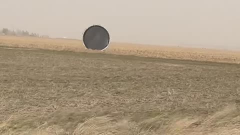 Trampoline Rolls Through Field