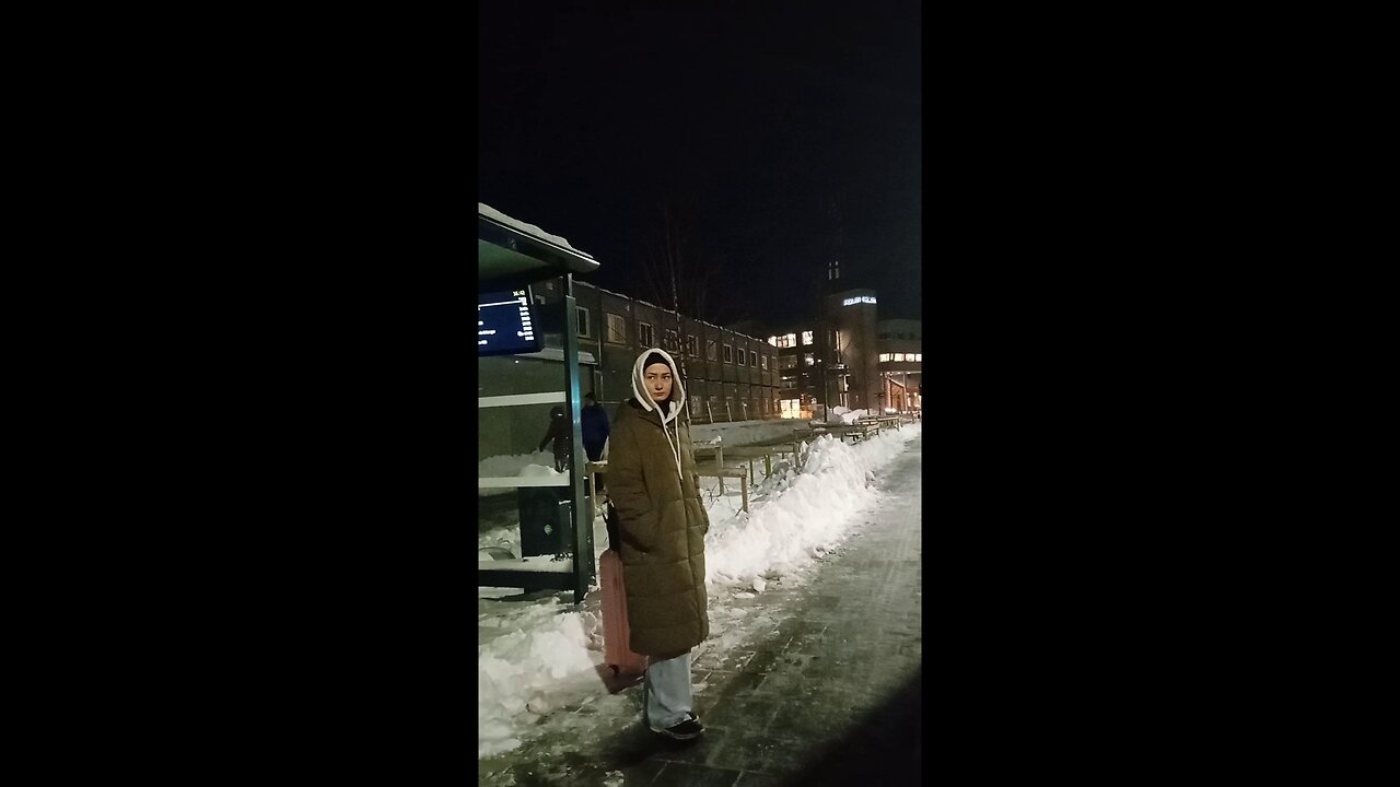Beautiful girl freezing in the northern frost of -7°C and wind, waiting for the bus.